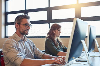 Buy stock photo Shot of two designers working on computers in an office