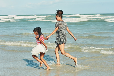 Buy stock photo Shot of a mother and her little daughter enjoying a walk along the beach