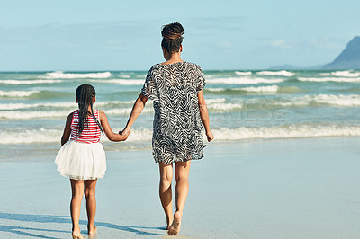 Buy stock photo Rear view shot of a mother and her little daughter enjoying a walk along the beach