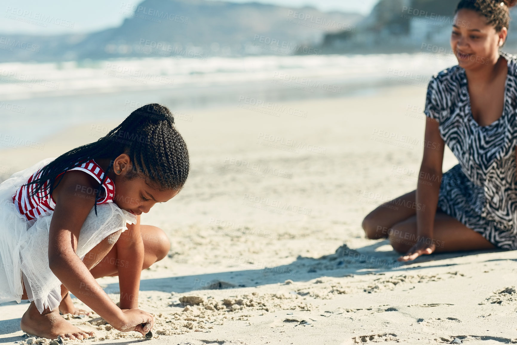 Buy stock photo Shot of a mother and her little daughter playing in the sand at the beach