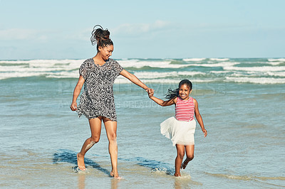 Buy stock photo Shot of a mother and her little daughter enjoying a walk along the beach