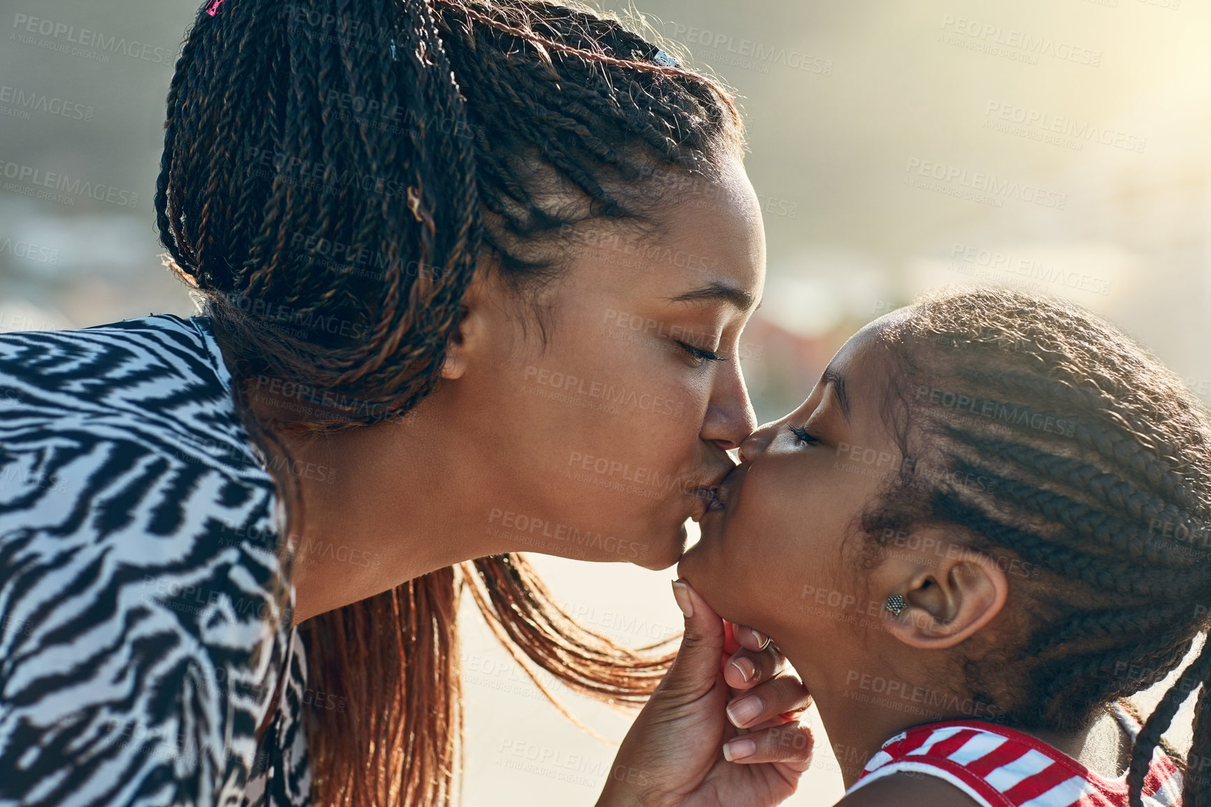 Buy stock photo Shot of a mother giving her little daughter a kiss at the beach