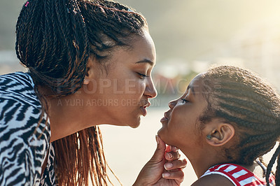 Buy stock photo Shot of a mother giving her little daughter a kiss at the beach