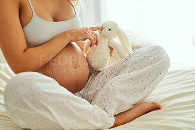 Buy stock photo Shot of a pregnant woman holding a stuffed toy while sitting on her bed