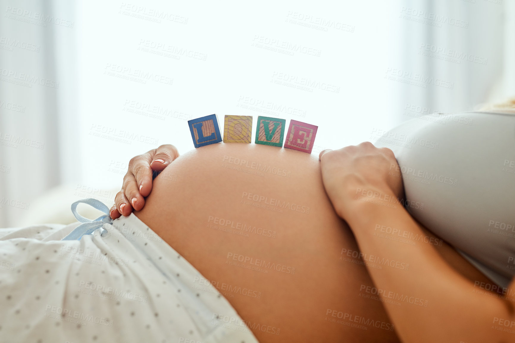 Buy stock photo Closeup shot of a pregnant woman lying down with wooden baby blocks on her belly