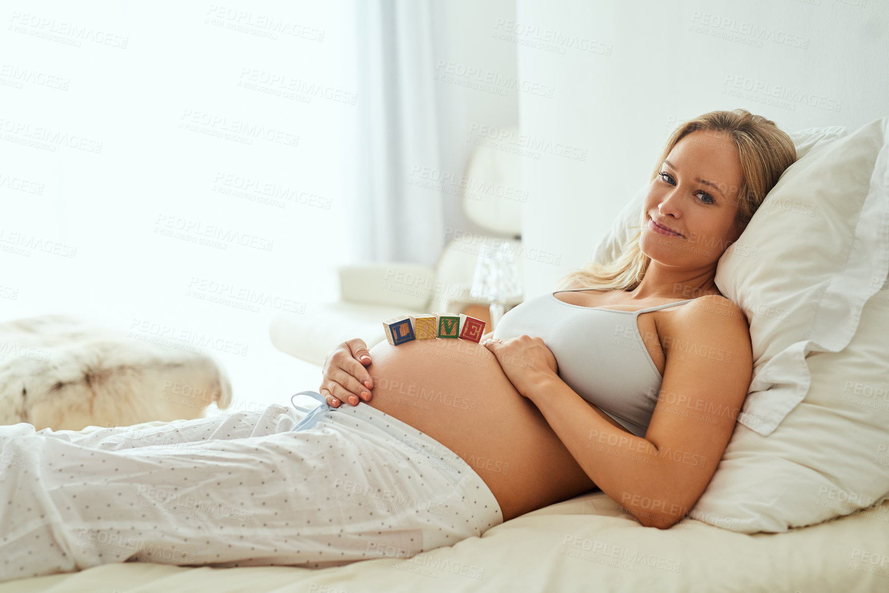 Buy stock photo Closeup shot of a pregnant woman lying down with wooden baby blocks on her belly