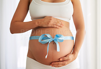 Buy stock photo Cropped shot of a woman with a blue ribbon tied around her pregnant belly