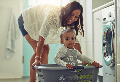 Buy stock photo Cleaning, mother and baby playing in basket doing the laundry in their home. Hygiene or clean for wellness, positive and happy family have fun bonding together at washing machine with lens flare