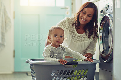 Buy stock photo Shot of a mother and her adorable baby boy doing the laundry at home