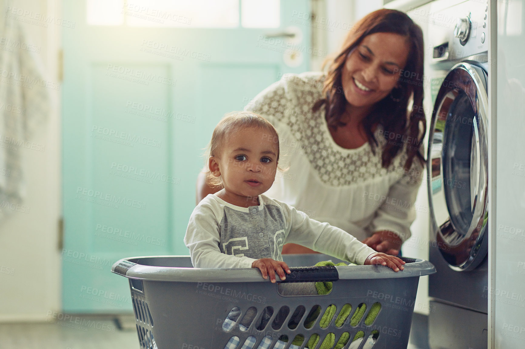 Buy stock photo Shot of a mother and her adorable baby boy doing the laundry at home