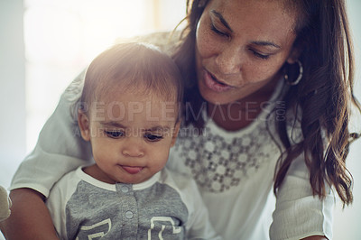 Buy stock photo Shot of a mother and her adorable baby boy looking at something at home