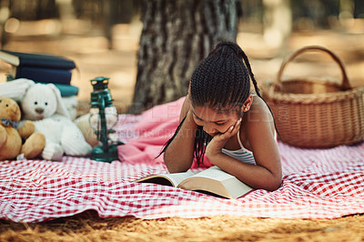 Buy stock photo Kid, girl and reading book on picnic in forest for story, fantasy and novel for child development. Female person, outdoor and happy with with toys in woods on break for information and knowledge. 