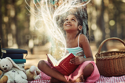 Buy stock photo Shot of a little girl reading a book with glowing pages in the woods