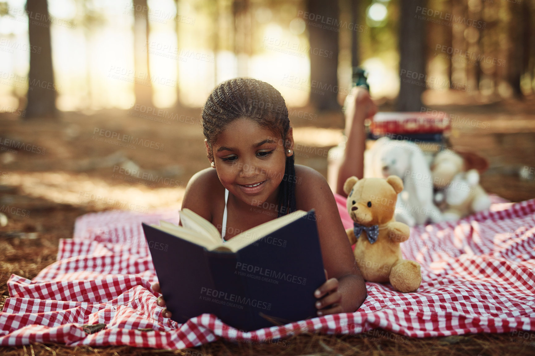 Buy stock photo Happy African kid, reading book and relax outdoor for learning, study or education in forest. Picnic blanket, park and girl with story, magic fantasy or fairytale knowledge on holiday with teddy bear