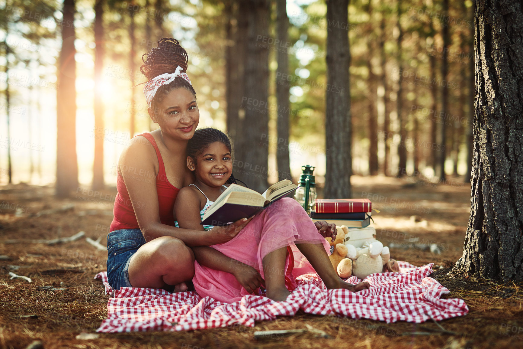 Buy stock photo Shot of a mother and her little daughter reading a book together in the woods