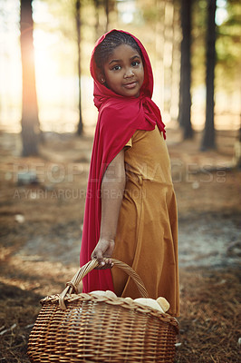 Buy stock photo Child, red and basket in forest for portrait, adventure and fairytale fantasy in nature. Girl, hamper and hood in woods for story themed birthday party, magic and cosplay at trees with creativity