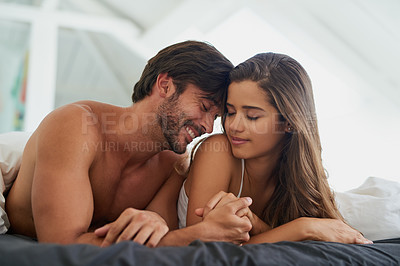 Buy stock photo Shot of a happy and affectionate young couple relaxing together in bed