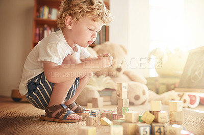 Buy stock photo Shot of an adorable little boy playing with wooden blocks at home