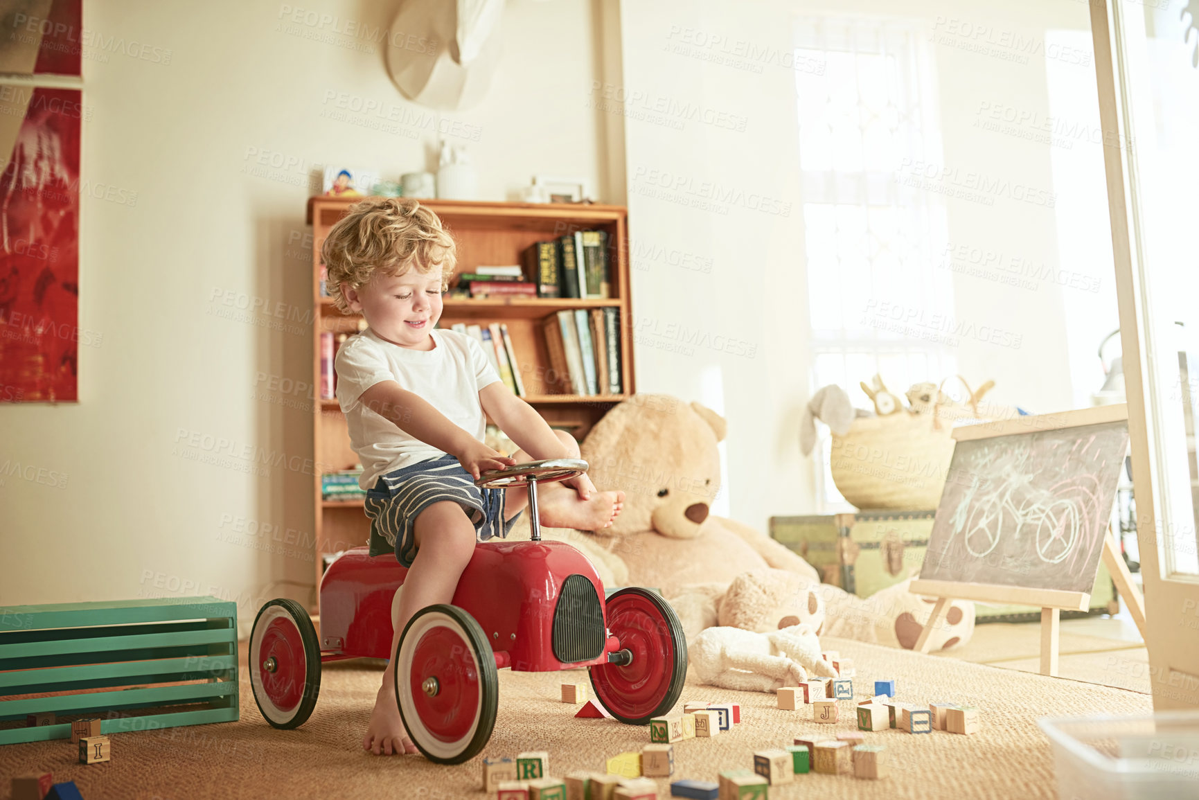 Buy stock photo Shot of a little boy playing on a toy car at home