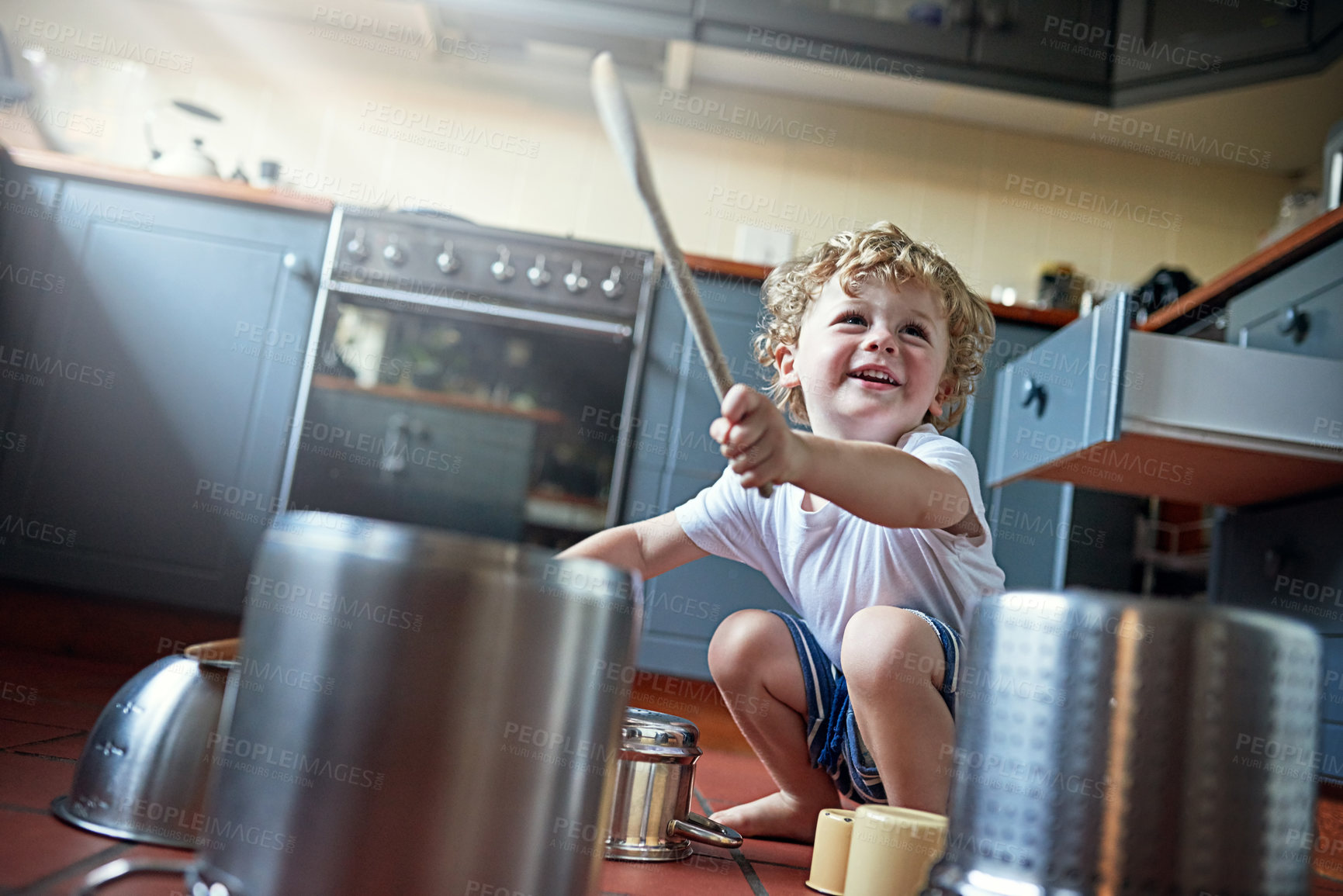 Buy stock photo Shot of an adorable little boy playing drums on a set of pots in the kitchen