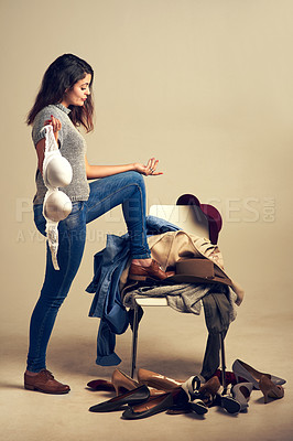 Buy stock photo Bra, clothes and question with woman in studio isolated on background for dressing or wardrobe decision. Chair, confused and pile of clothing with retail customer shopping for fashion outfit