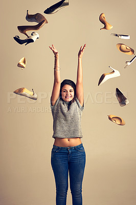 Buy stock photo Studio shot of a joyful young woman throwing a bunch of shoes in the air against a brown background
