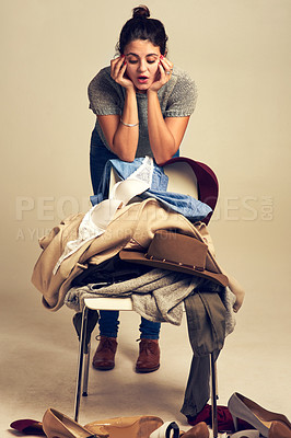 Buy stock photo Choice, studio and girl with clothes in pile on chair for outfit planning, wardrobe decision or option and shopping. Fashion designer, isolated and background for garment sorting for styling session.