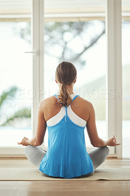 Buy stock photo Rearview shot of a young woman practicing yoga at home