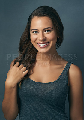 Buy stock photo Studio shot of a beautiful young woman smiling against a blue background
