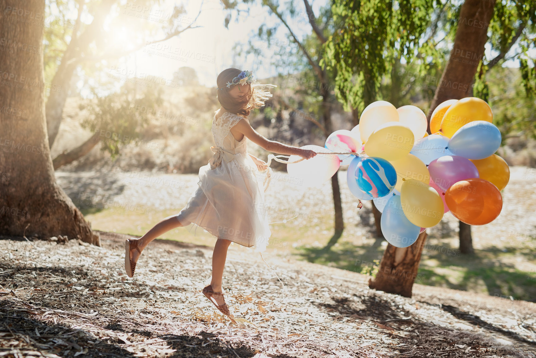 Buy stock photo Shot of a little girl playing with a bunch of balloons outside