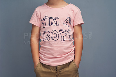 Buy stock photo Boy, child and point at text on shirt for gender identity, style and edgy fashion model by gray background. Person, toddler or kid with pink clothes for choice, learning and show print with promotion