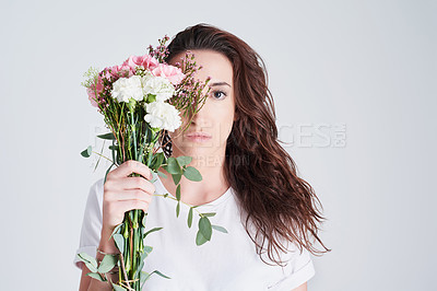 Buy stock photo Spring, woman and portrait with flowers in studio with nature aesthetic or eco friendly arrangement on gray background. Person, floral bouquet or face with gift, serious or mockup with sustainability