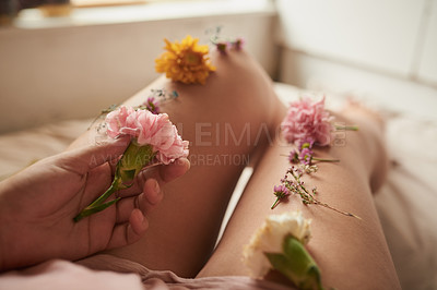 Buy stock photo Shot of an unidentifiable young woman lying in bed with flowers arranged on her legs