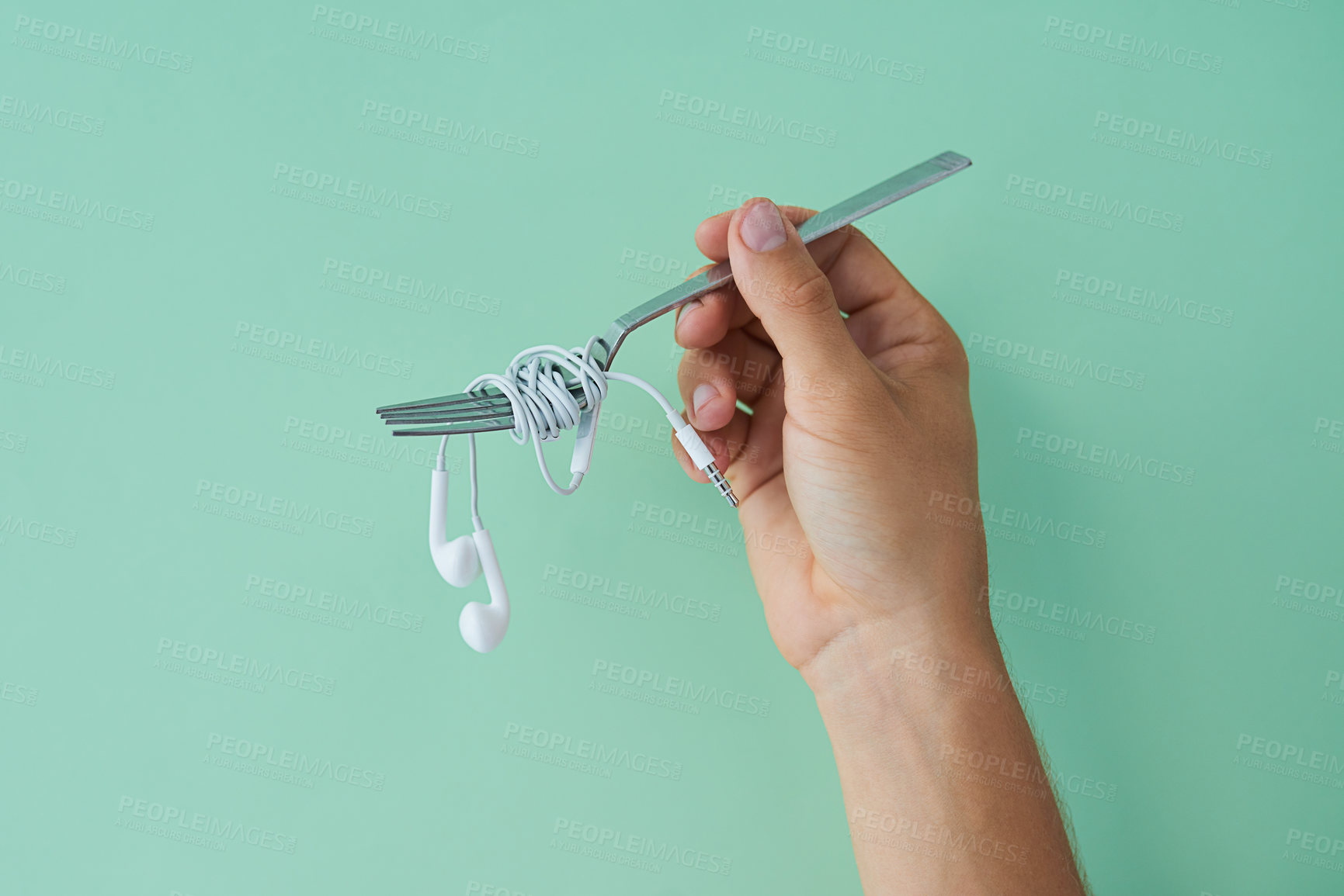 Buy stock photo Cropped studio shot of a man holding earphones wrapped around a fork against a turquoise background