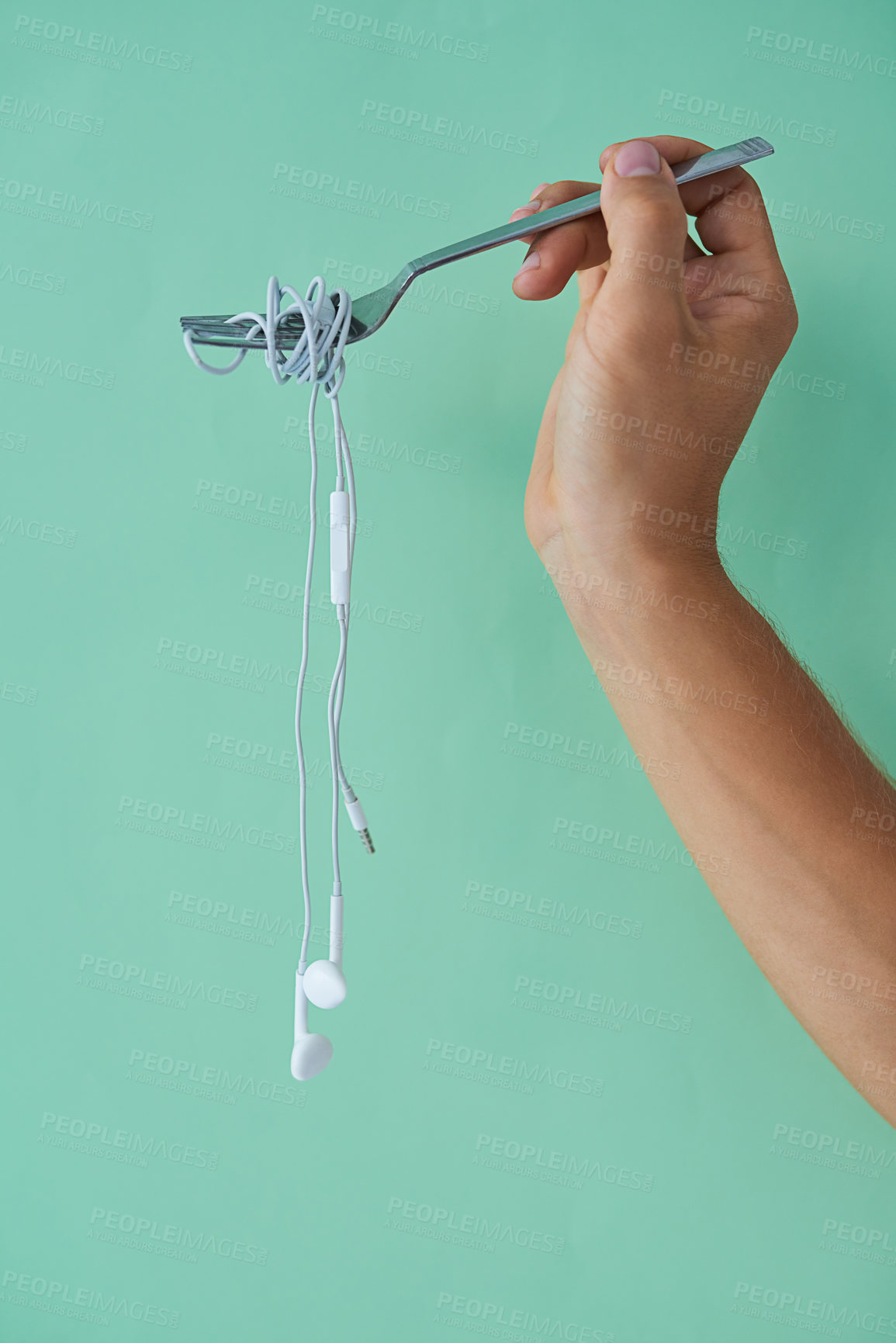 Buy stock photo Cropped studio shot of a man holding earphones wrapped around a fork against a turquoise background