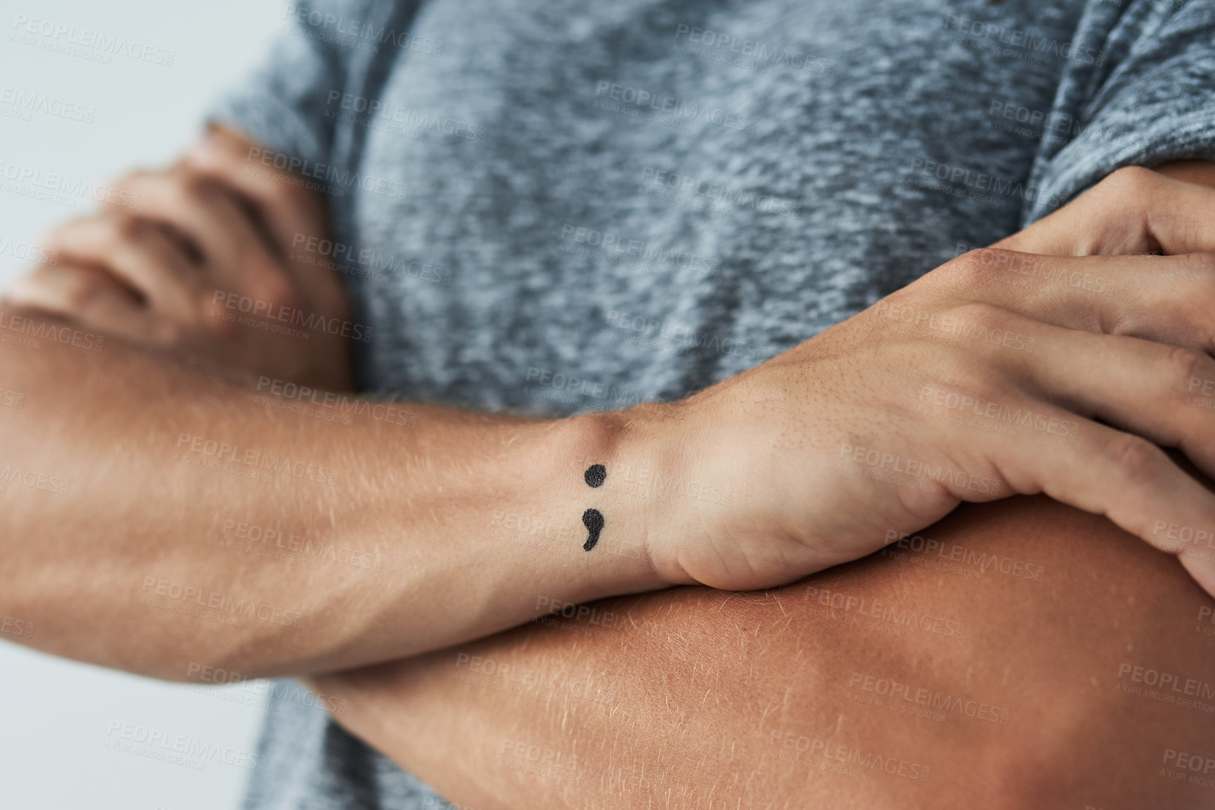 Buy stock photo Studio shot of an unrecognizable man with a semi colon tattoo standing with his arms folded