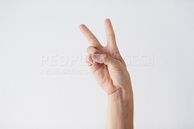 Buy stock photo Cropped shot of a unrecognizable person's hands against a grey background showing the peace sign
