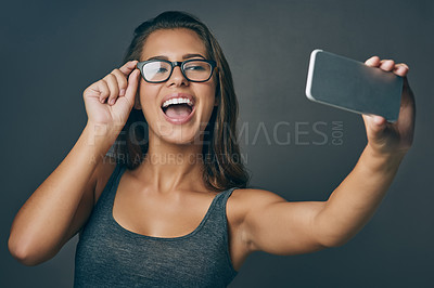 Buy stock photo Woman, studio and excited with eyeglasses on selfie on grey background for eyesight and eyewear prescription. Female person, happy and confident with social media post or profile picture with frame