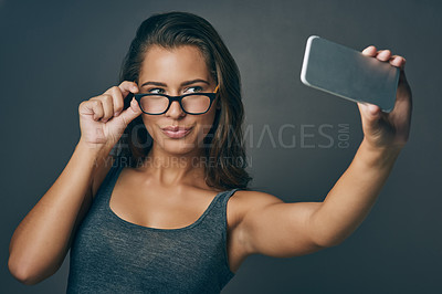 Buy stock photo Woman, studio and serious with eyeglasses on selfie on grey background for eyesight and eyewear prescription. Female person, satisfied and confident with social media post, profile picture and frame