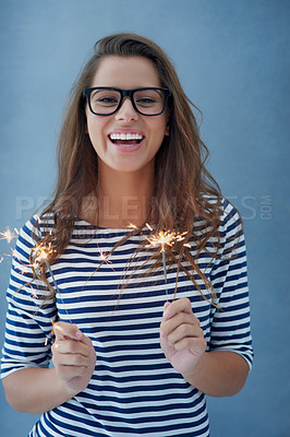 Buy stock photo Studio shot of a beautiful young woman holding sparklers against a blue background