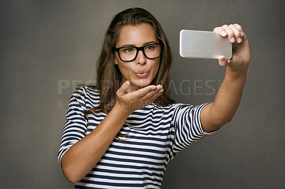 Buy stock photo Woman, kiss and selfie with glasses in studio for social media post, eyewear update and prescription for vision. Girl, photography and gray background with spectacles for eye care and optometry.