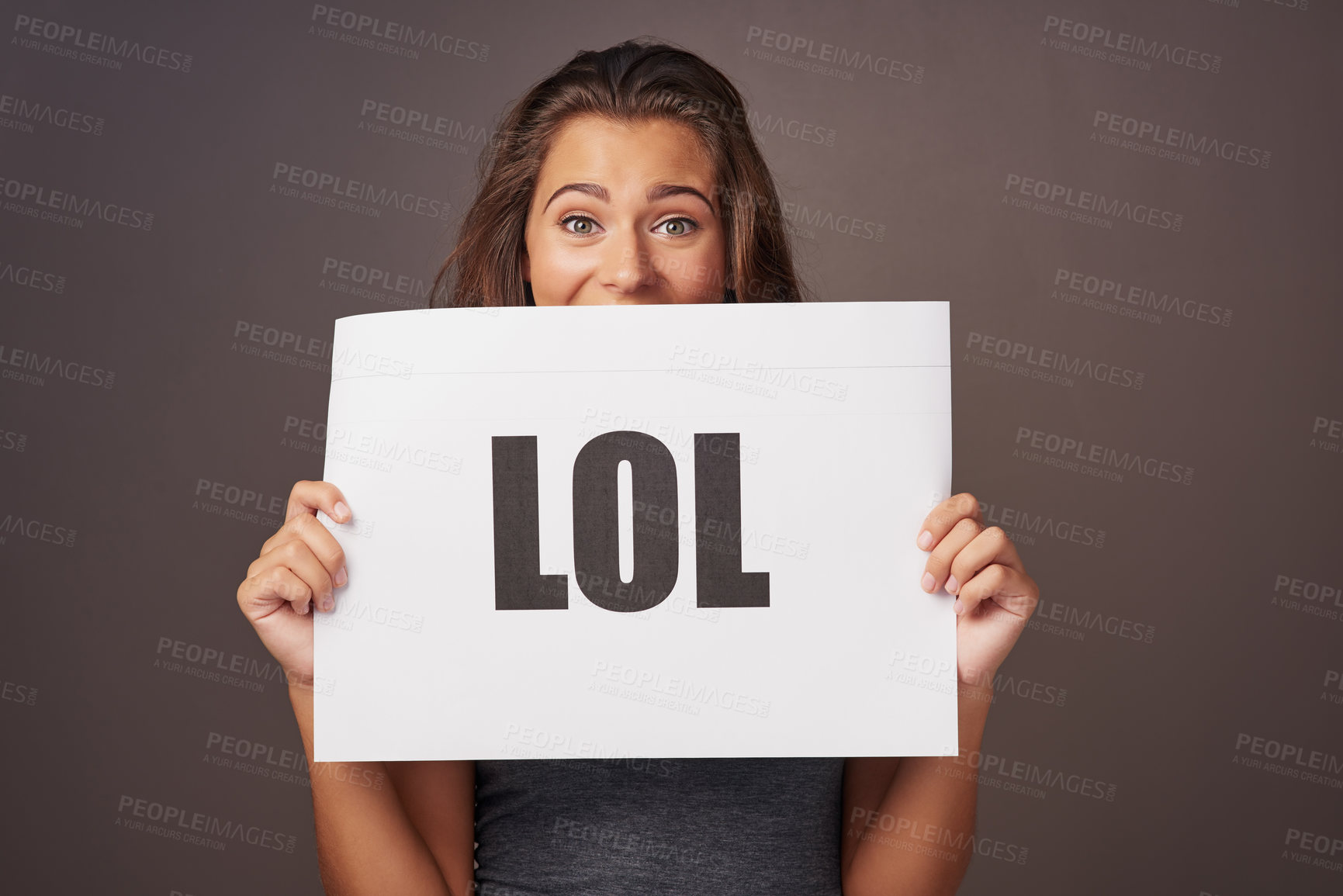 Buy stock photo Studio shot of a young woman holding a sign with “lol” printed on it against a gray background