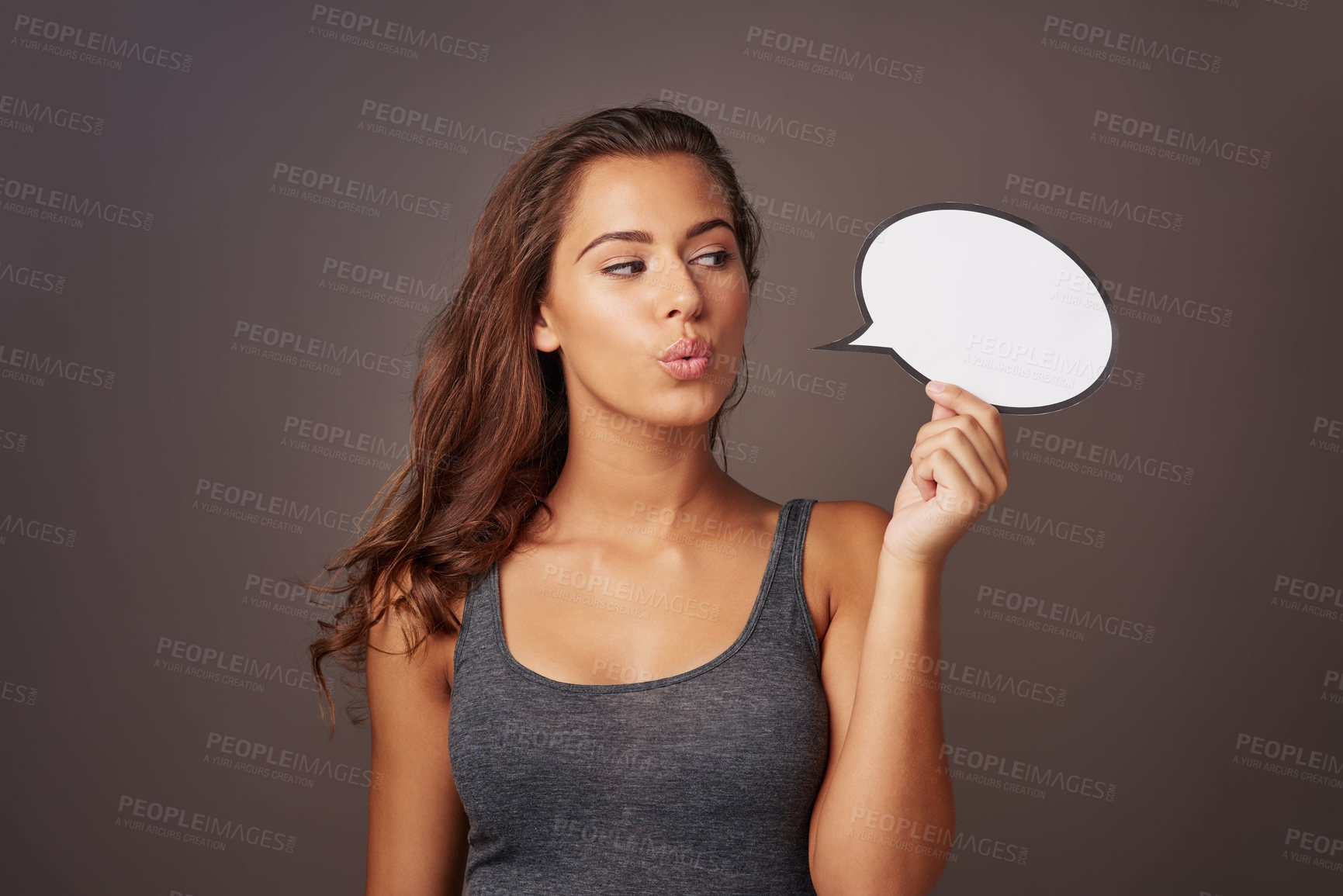 Buy stock photo Studio shot of an attractive young woman holding a blank speech bubble against a gray background