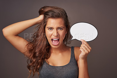 Buy stock photo Studio shot of an attractive young woman holding a blank speech bubble and shouting against a gray background