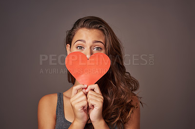 Buy stock photo Studio shot of an attractive young woman holding a blank red heart against a gray background