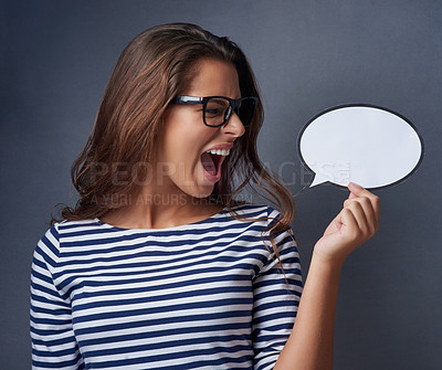 Buy stock photo Studio shot of an attractive young woman holding a blank speech bubble and shouting against a gray background
