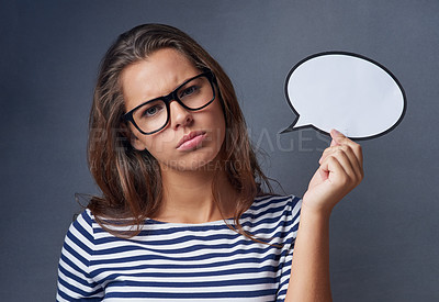 Buy stock photo Studio shot of an attractive young woman holding a blank speech bubble and looking angry against a gray background