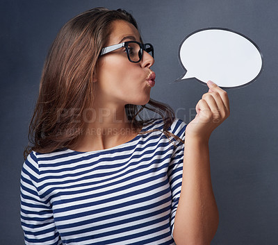 Buy stock photo Studio shot of an attractive young woman holding a blank speech bubble against a gray background