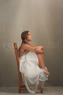Buy stock photo Studio shot of an attractive young woman looking thoughtful while sitting on a chair