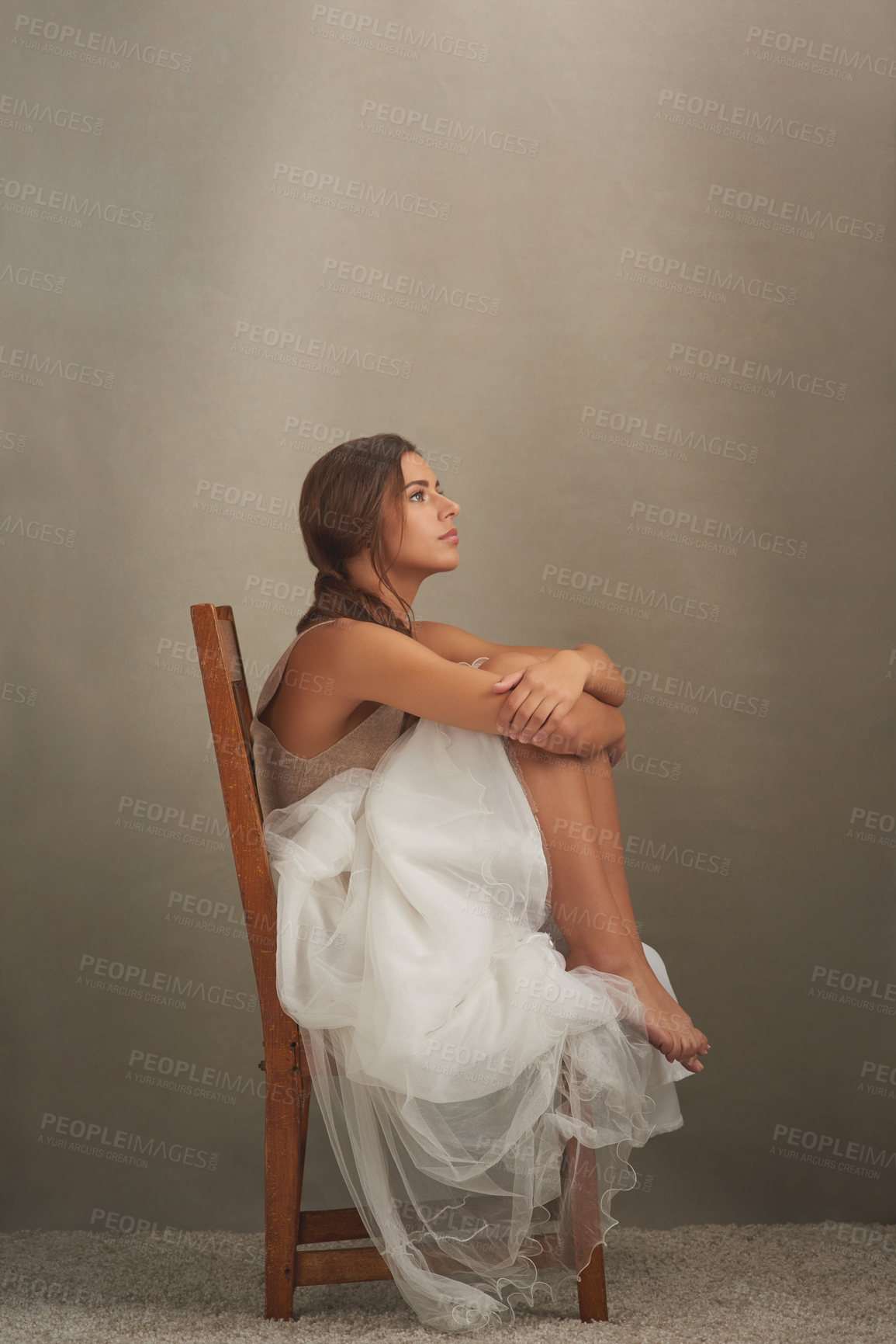 Buy stock photo Studio shot of an attractive young woman looking thoughtful while sitting on a chair